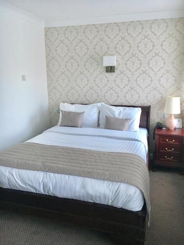 a bedroom with a large bed with white sheets and pillows at Normanton Park Hotel, Sure Hotel Collection by Best Western in Oakham