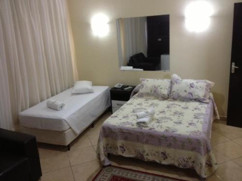 a hotel room with two beds and a mirror at Hotel Monte Libano in Paranaguá