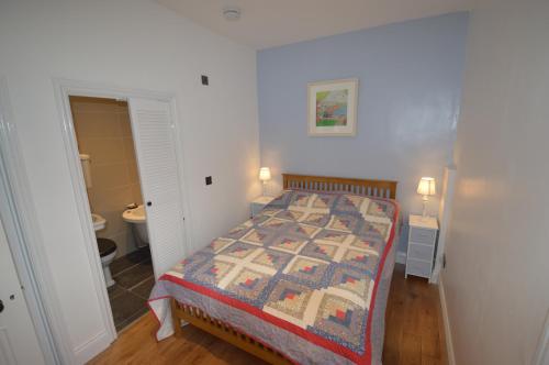 a bedroom with a bed with a quilt on it at Little Weech in Dawlish