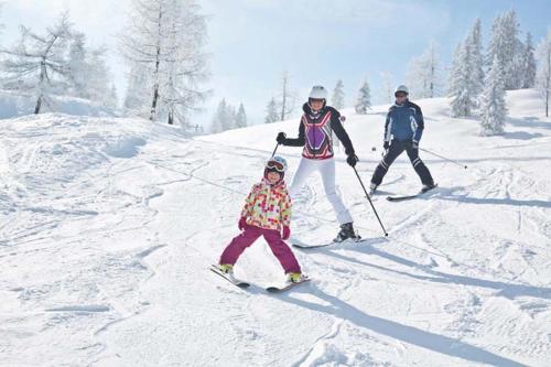 two adults and a child on skis in the snow at Ferienwohnung Biechl-Hauser Doris in Sankt Ulrich am Pillersee