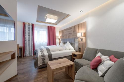 a hotel room with a bed and a couch at Hotel Mondin in Ischgl