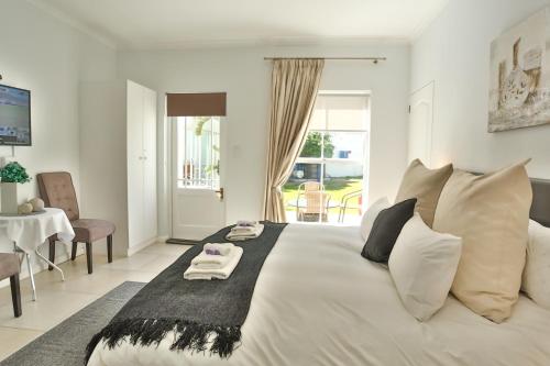 a bedroom with a large white bed with a table and chairs at Abington Manor Fish Hoek Guesthouse in Fish hoek