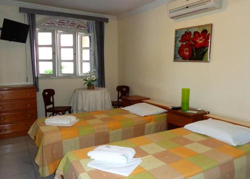 a hotel room with two beds and a table at Pousada Monjope in Igarassu