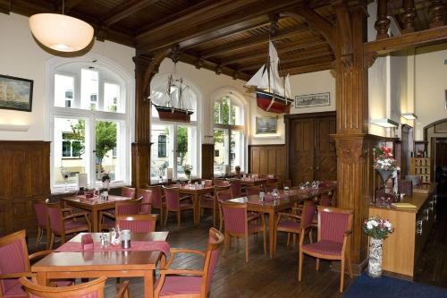 ein Restaurant mit Holztischen, Stühlen und Fenstern in der Unterkunft Restaurant & Hotel Wismar in Wismar