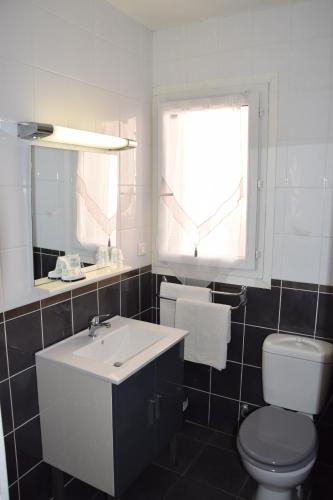a bathroom with a sink and a toilet and a window at Hôtel le Grillon in LʼÎle-Rousse