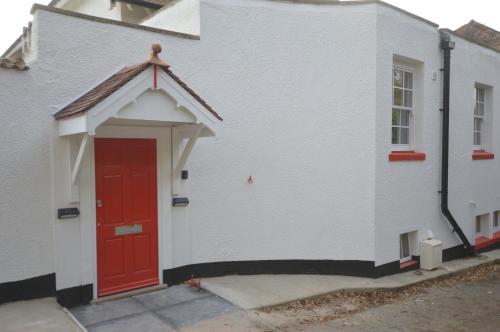 a red door on the side of a white building at Little Weech in Dawlish