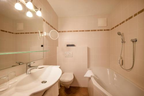 a bathroom with a tub and a toilet and a sink at Berghotel Hochfügen in Hochfugen