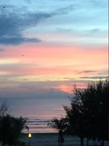 a sunset on the beach with a person walking on the beach at Studio Apartment @ Gold Coast Morib Banting Malaysia in Morib