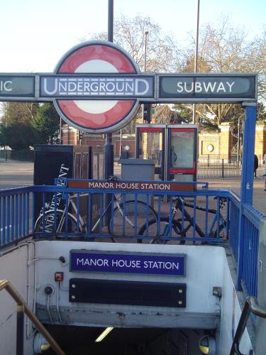 a bus stop with a sign for a manor house station at Beaconsfield Hotel in London