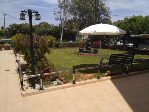 a park bench with an umbrella in a park at Melia Studios in Kato Daratso