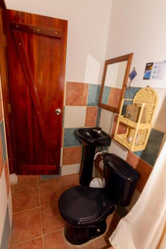 a bathroom with a black toilet and a mirror at Tuzco Lodge in Puerto López