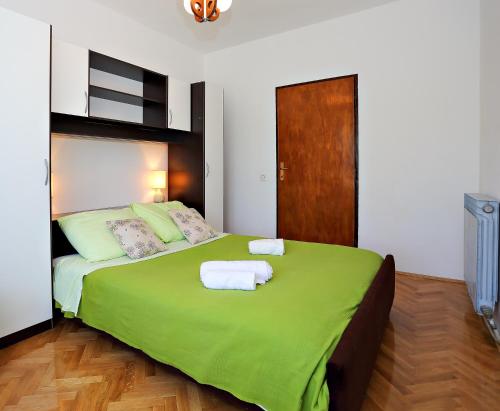 a bedroom with a green bed with towels on it at Apartmani Nena in Ždrelac