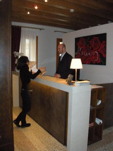 a woman standing at a counter talking to a man at UNAHOTELS Eco Hotel Villa Costanza Venezia in Mestre