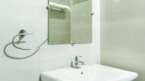 a white bathroom with a sink and a mirror at Blue Ocean Sands - On the Beach in Kumta