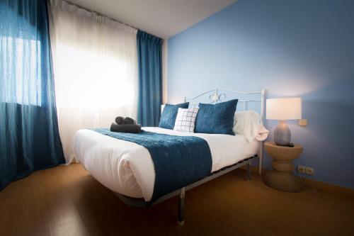 a bedroom with a bed with blue walls and a window at Holidays2Riviera Sea Side Front Beach in Mijas Costa