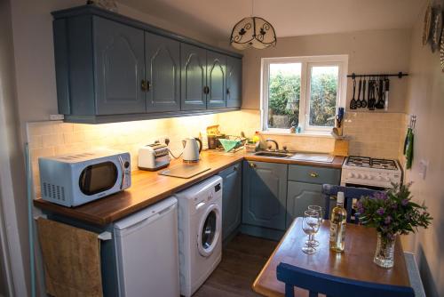 a kitchen with blue cabinets and a table with a microwave at Barney's Lodge in Malin