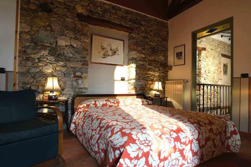 1 dormitorio con cama y pared de piedra en Il Cortile - Casa d'Artista, en Casalzuigno