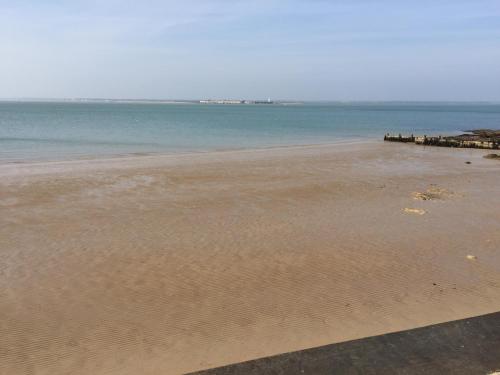 a sandy beach with a pier in the water at Mountfield in Freshwater