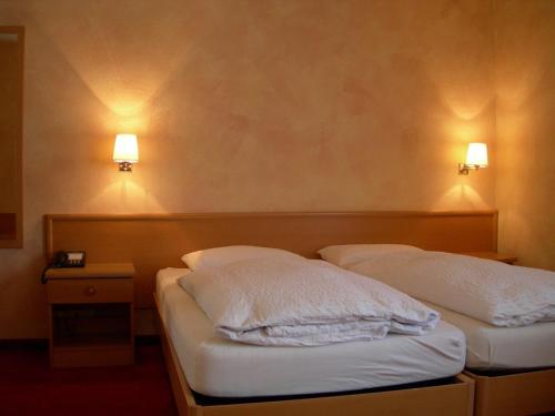 two beds in a room with two lights on the wall at Hotel Crystal Interlaken in Interlaken