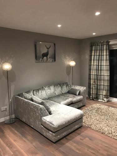 a living room with a couch and a deer on the wall at Carriage Cottage Hot Tub in Beith