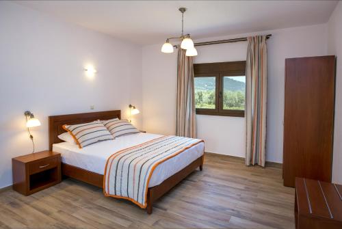a bedroom with a bed and a window at Elaionas Stone Houses in Skala Potamias