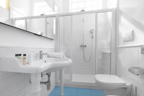 a white bathroom with a sink and a toilet at Hotel Bougainville in Positano