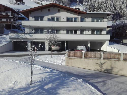 a house in the snow with cars parked in it at Apart Alpin in Hippach