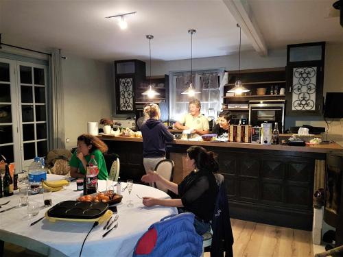 a group of people sitting around a table in a kitchen at Nid dans la forêt in Saint-Jean-aux-Bois