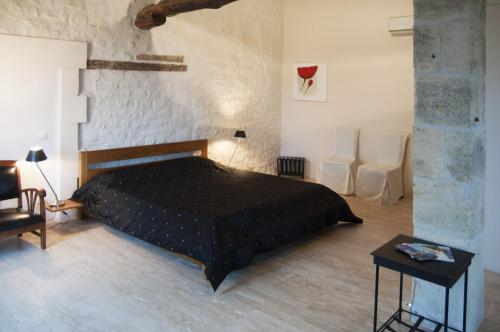 a bedroom with a black bed and two white chairs at Chambre d'Hôtes Clos des Pierres Blanches in Brie-sous-Archiac