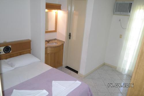 a small bedroom with a bed and a sink at Hotel Pousada Ilha do Mar Bombinhas in Bombinhas