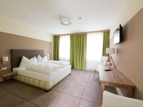 um quarto de hotel com uma cama, uma secretária e janelas em Landgasthof zum Goldenen Hirschen em Bierbaum am Kleebühel