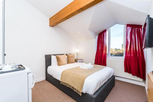 a bedroom with a bed with red curtains and a window at Riverbank Stay in London