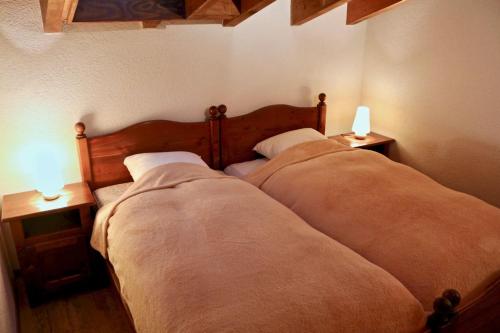オヴロナにあるAu centre d'Ovronnaz - Chalet mitoyenのベッド2台、テーブル上のランプ2つが備わるベッドルーム1室