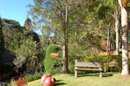 a park bench sitting in the grass next to a tree at Pássaro de Fogo in Santo Antônio do Pinhal