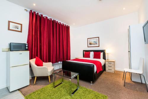 a bedroom with a bed and a red curtain at Riverbank Stay in London