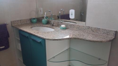 eine Badezimmerablage mit Waschbecken und Spiegel in der Unterkunft Maravilhosa Villa com Piscina in Arraial do Cabo