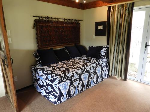 a bedroom with a bed with a black and white comforter at O Naturel Vineyard Stay in Cromwell