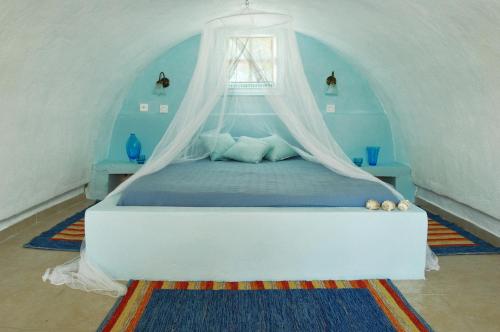 a bedroom with a bed with a mosquito net at Aeolis Santorini in Perissa