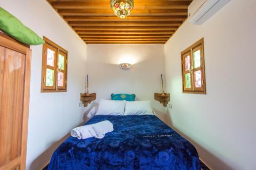 a bedroom with a bed with a blue comforter and two towels at Dar Mfaddel in Fès