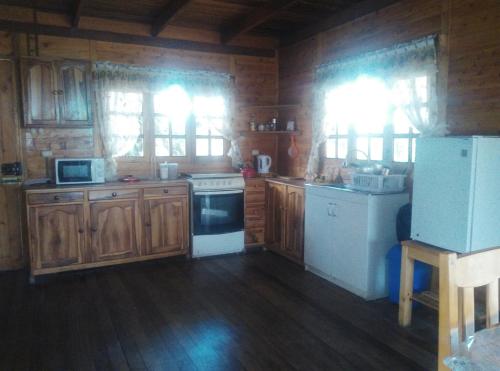 una cocina con armarios de madera y electrodomésticos blancos en Cabañas Típicas ARIAS, en Oxapampa