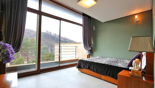 a bedroom with a bed and a large window at Hugel Heim Pension in Pyeongchang 