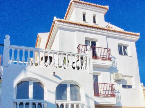 a white building with red balconies and a blue sky at Casa Buenavista in Almuñécar