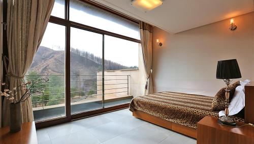 a bedroom with a large window with a mountain view at Hugel Heim Pension in Pyeongchang 