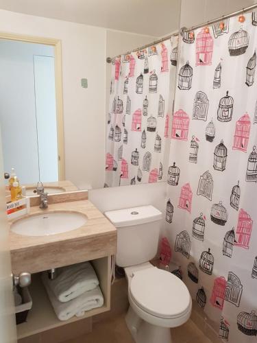 a bathroom with a toilet and a sink and a shower curtain at Departamento Laguna Bahia Algarrobo in Algarrobo