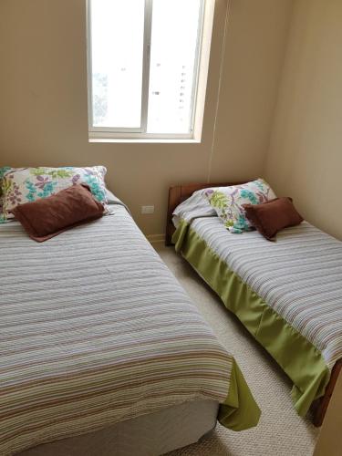 two beds in a small room with a window at Departamento Laguna Bahia Algarrobo in Algarrobo
