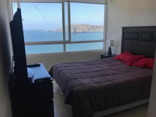1 dormitorio con cama y vistas al océano en Departamento Arenas La Herradura, en Coquimbo