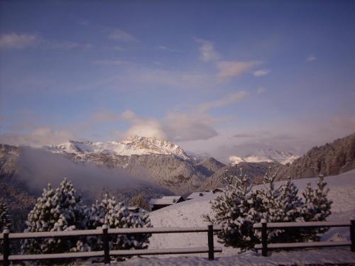 a view of a snowy mountain range with a fence at Albergo Riglarhaus in Sauris