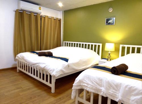 duas camas num quarto com paredes verdes em Cosy Town Home at the Old City em Chiang Mai