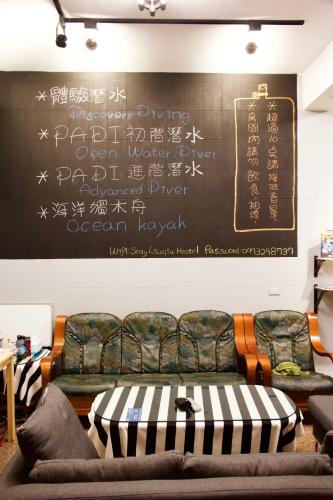 a living room with two couches and a chalkboard at Stay Liuqiu Diving Hostel in Xiaoliuqiu