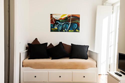 リスボンにあるApartamento ideialの白いベッド(黒い枕付)と壁画